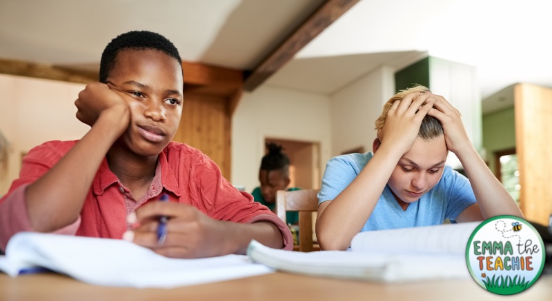 Two bored students, one resting his cheek on his hand and the other with his head in his hands.