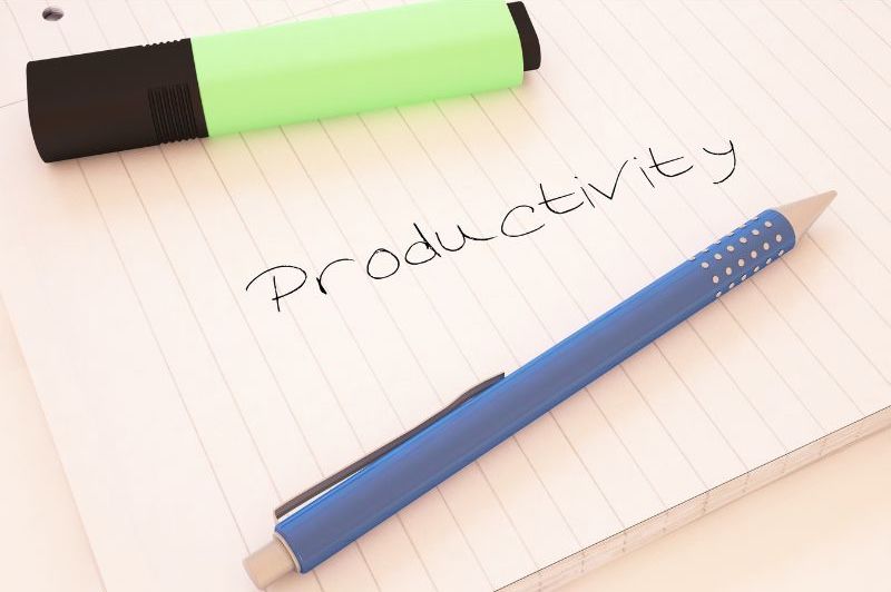 An image of a notebook page with the word “productivity” written on it. There is also a blue pen and a green highlighter laying on the piece of paper. Increasing productivity will maximize planning time.