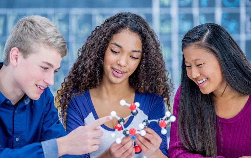 A group of three students working together with a molecular model.